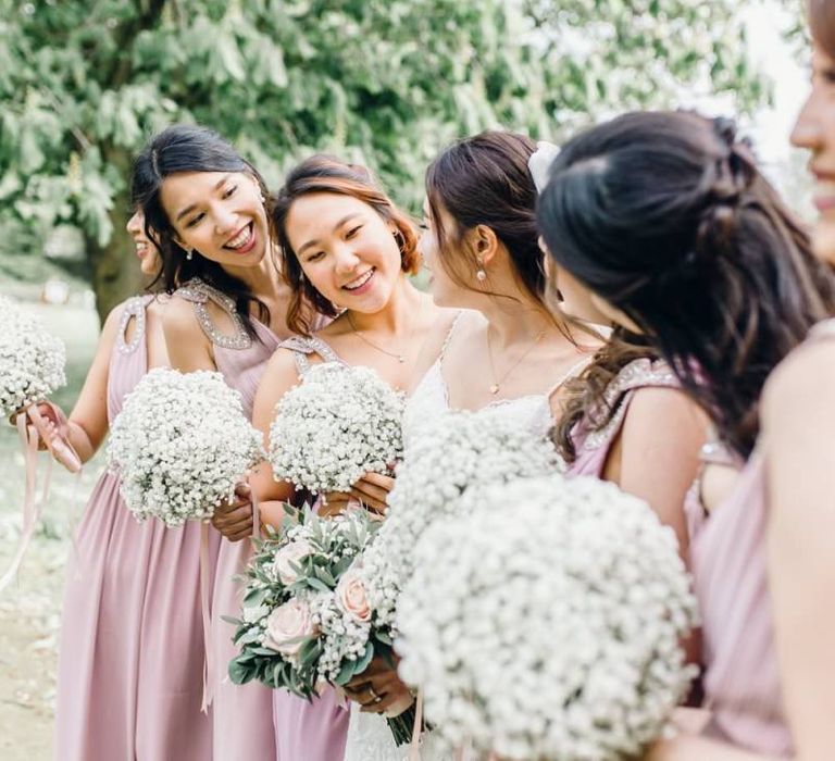 Bridesmaids in dusky pink dresses for traditional celebration with gypsophila bouquets