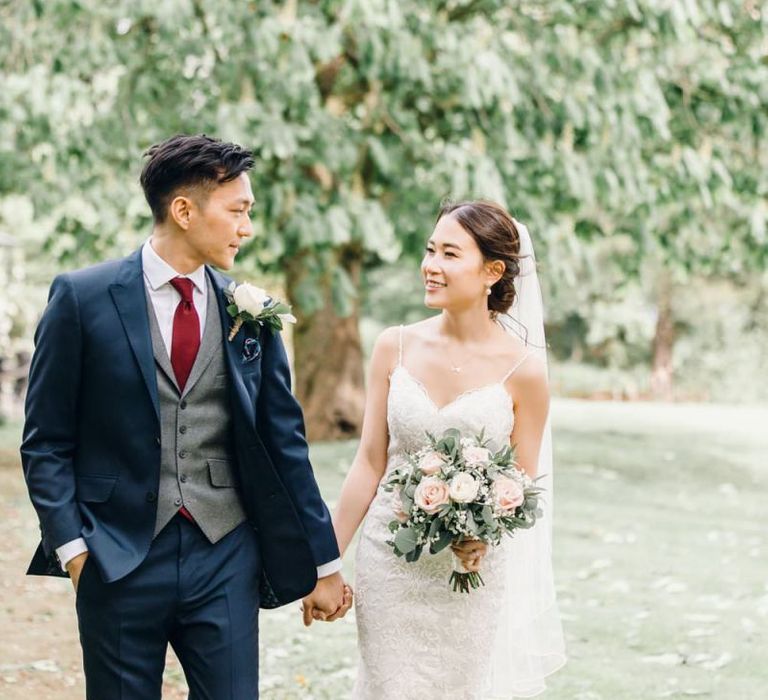 Bride and groom steal a moment at wedding reception with rose and gypsophila bouquets