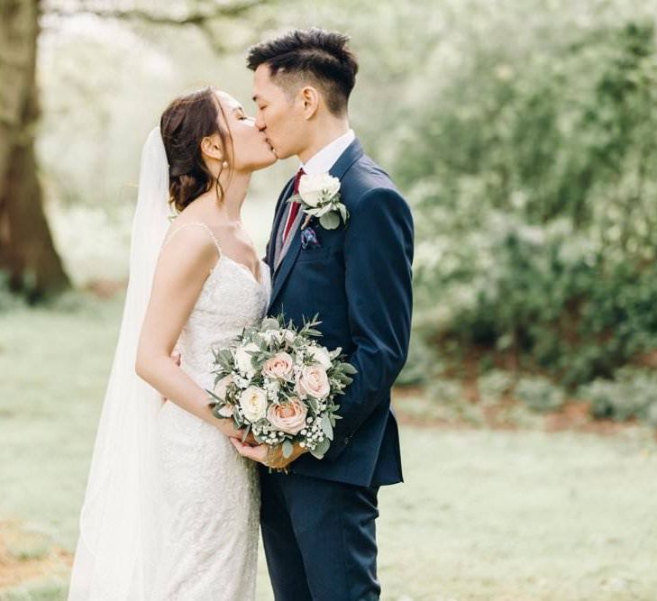 Bride wearing a delicate lace dress with rose and gypsophila bouquets  and groom in three piece suit with grey waistcoat