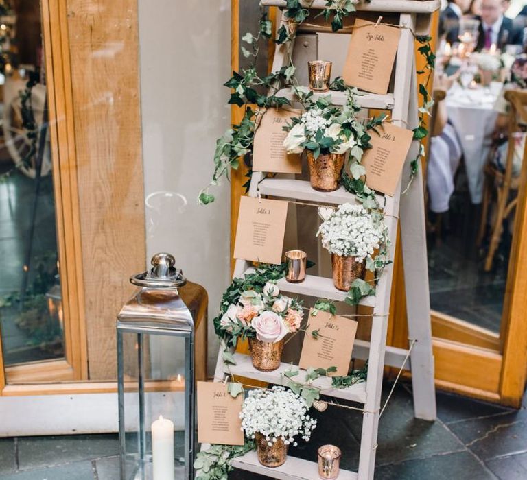 Rustic styled table plan with rose gold detailing and gypsophila arrangements