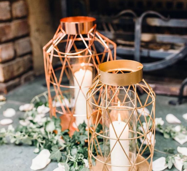 Rose gold candle lanterns with green foliage at rustic styled reception