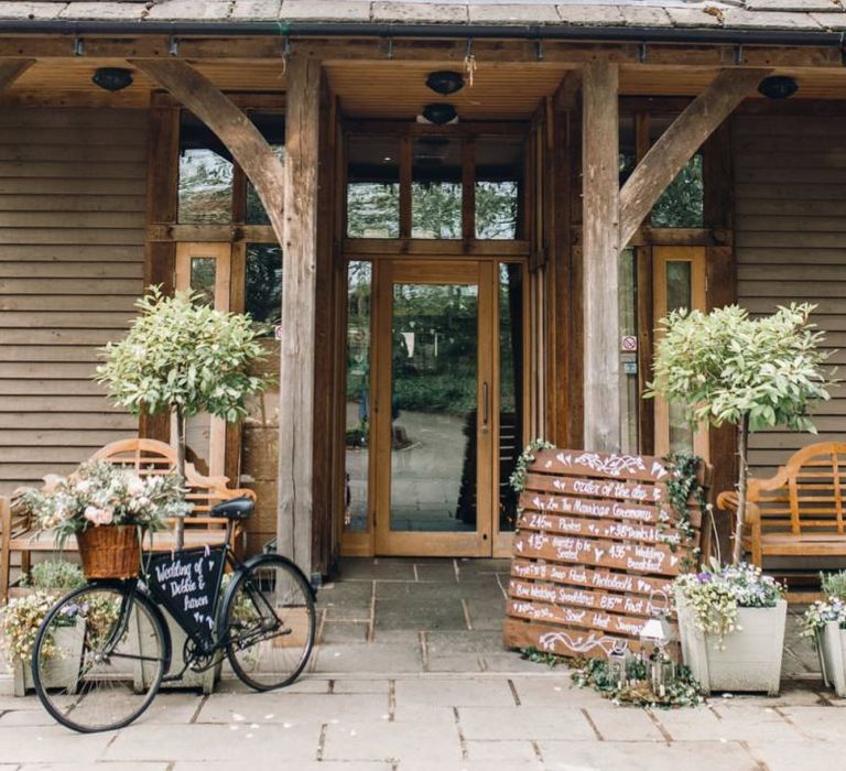 Entrance to wedding reception with rustic wedding bike and wooden pallet sign