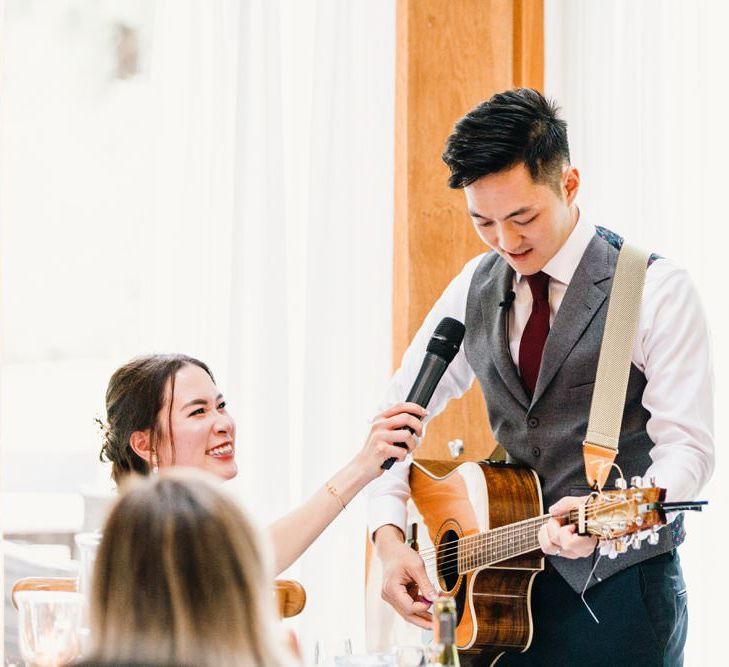 Groom serenades his bride with a guitar performance at wedding reception speeches