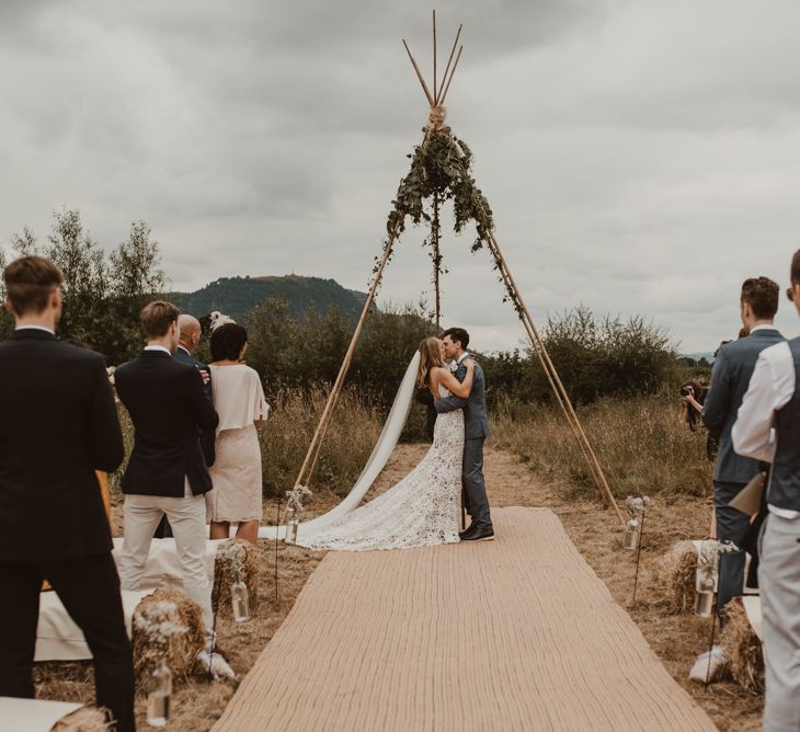 Bride in Sasha Dress by Made With Love with Crochet Finish, Fishtail Train, V-Neck and Plunging Back | Groom in Light Blue Two-Piece Suit by Hugo Boss | Blush Pink Buttonhole | Hessian Aisle | Hay Bales with White Blankets | Yurt Wedding with Outdoor Naked Tipi Ceremony, Glitter Station &amp; Peach Rewritten Bridesmaid Dresses | Nesta Lloyd Photography