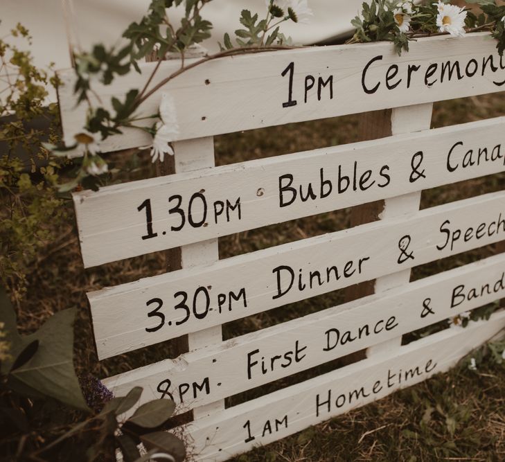 White Pallet Order of the Day Sign | Yurt Wedding with Outdoor Naked Tipi Ceremony, Glitter Station &amp; Peach Rewritten Bridesmaid Dresses | Nesta Lloyd Photography