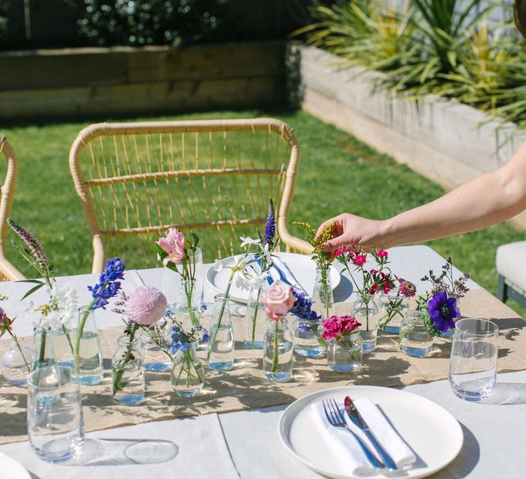 Person putting the finishing touches to a floral wedding centrepiece using vibrant colourful flowers for a garden wedding