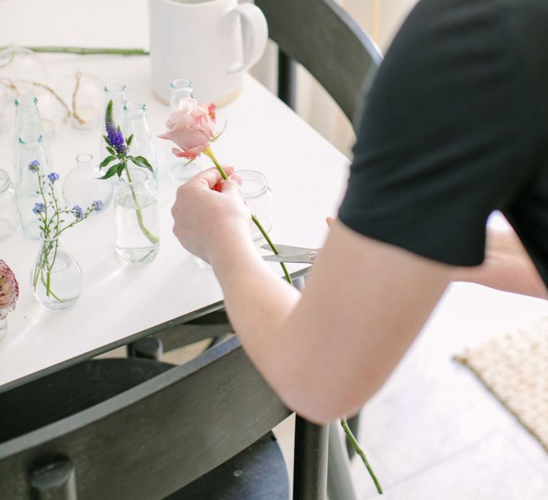 Person cutting an antique pale pink rose for a floral wedding centrepiece