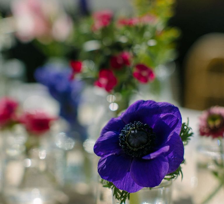 Close up of a vibrant purple anemone in a bud vase as part of a floral wedding centrepiece