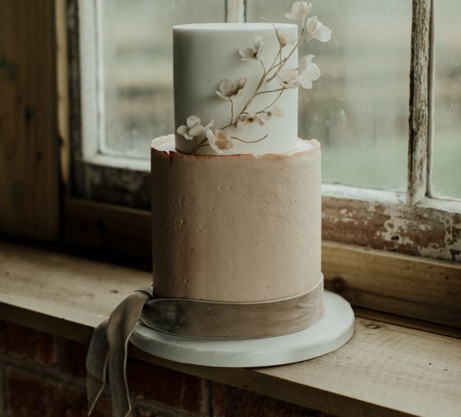 Pink and white wedding cake with delicate flower decor and velvet ribbon