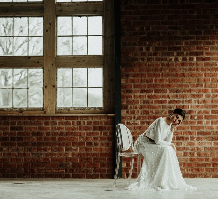 Bride in bridal crop top and sequin skirt sitting on a Ghost chair