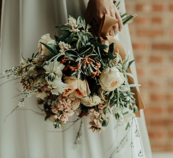 Muted flower wedding bouquet tied with ribbon and bridal crop top