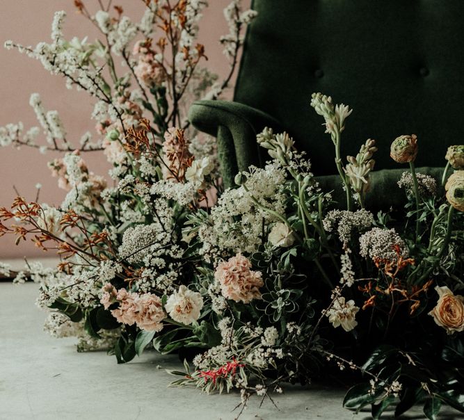 Emerald green velvet sofa and muted flower installation