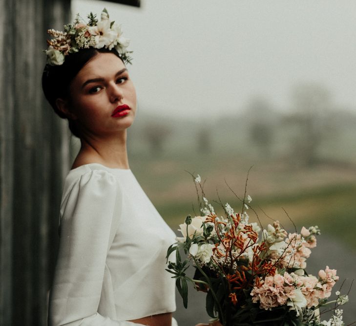 Beautiful bride with red lipstick holding an earthy bouquet in a bridal crop top