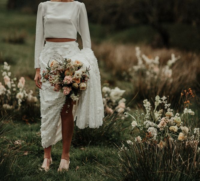 Boho bride in satin bridal crop top and sequin bridal skirt in a field