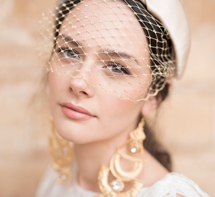 Beautiful Bride with Natural Makeup and On-Trend Turban Headband with birdcage Veil and Statement Gold Earrings