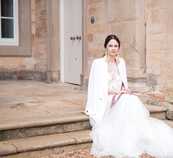 Stylish Bride in Jesus Peiro Wedding Dress with White Jacket, Sleek Back Hair &amp; Statement Gold Earrings