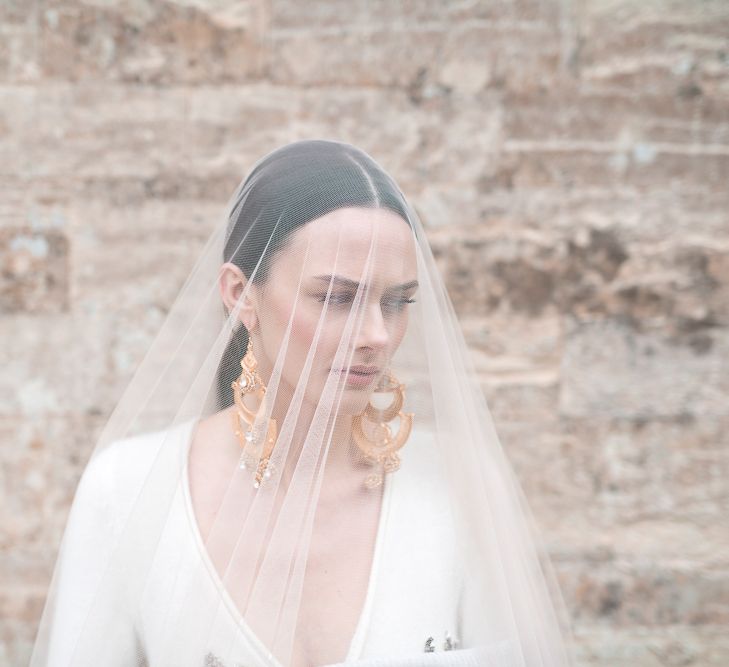 Bride in Sheer Bridal Veil Showing off Statement Earrings and Sleek Hairstyle