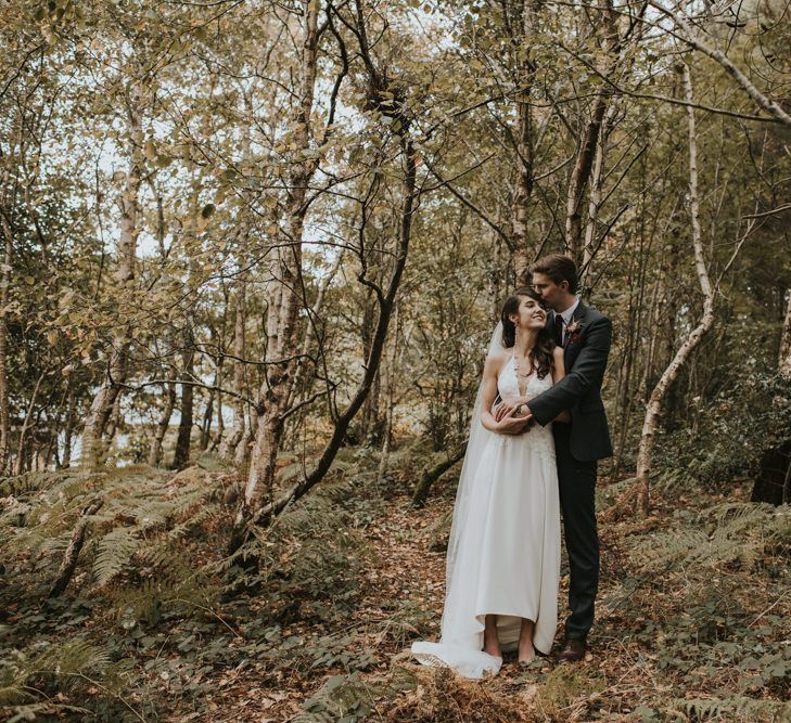 Groom in Tweed Suit  Embracing His Bride in Elbeth Gillis Wedding Dress in the Woods