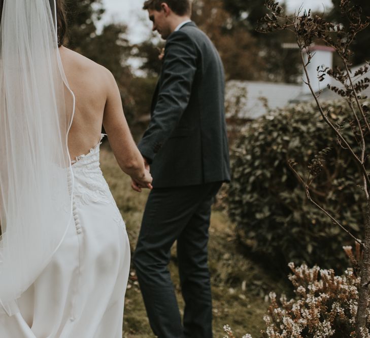 Bride in Elbeth Gillis Wedding Dress and Groom in  Tweed Suit  Holding Hands