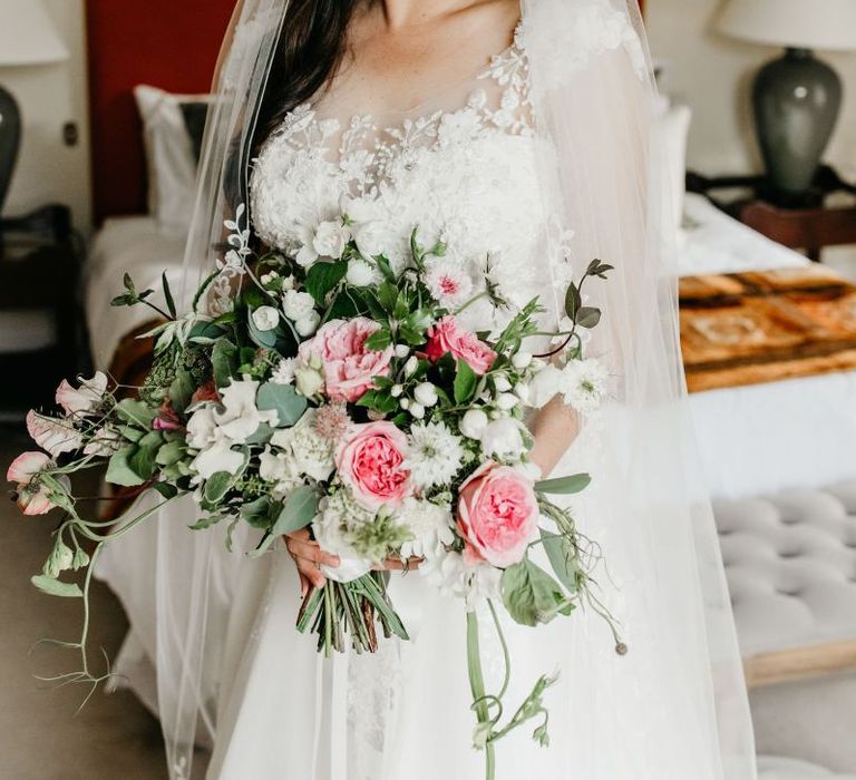 Bride in lace and tulle wedding dress golding a pink and white wedding bouquet