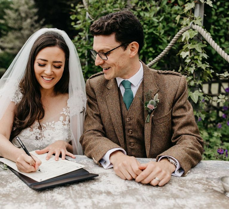 Bride and groom signing the register at socially distanced wedding