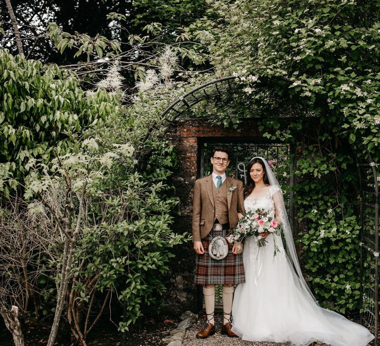 Bride in lace and tulle wedding dress and groom in tartan kilt at micro