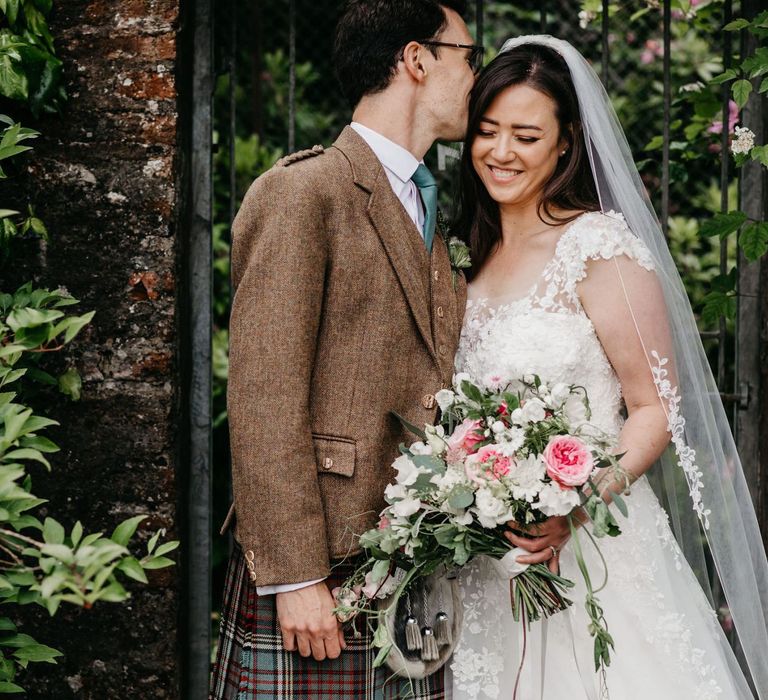 Groom in wool jacket kissing his bride on the head