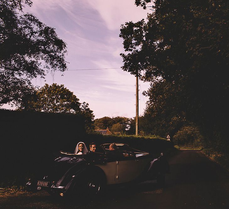 Bride and groom travelling in style in  a vintage convertible