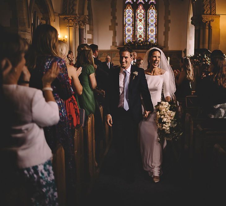 Bride and groom tie the knot at traditional church wedding ceremony with white rose bouquet