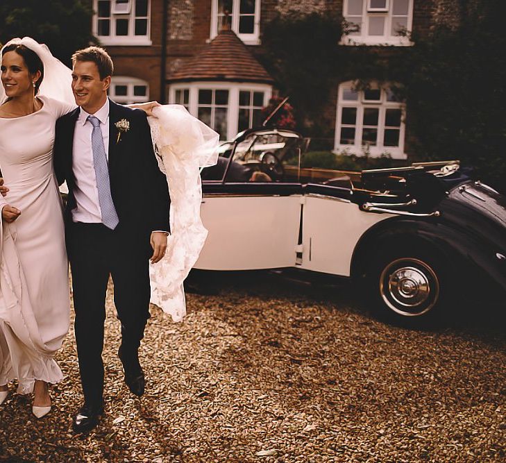 Bride wearing classic dress and long veil with groom looking dapper with a pale blue tie