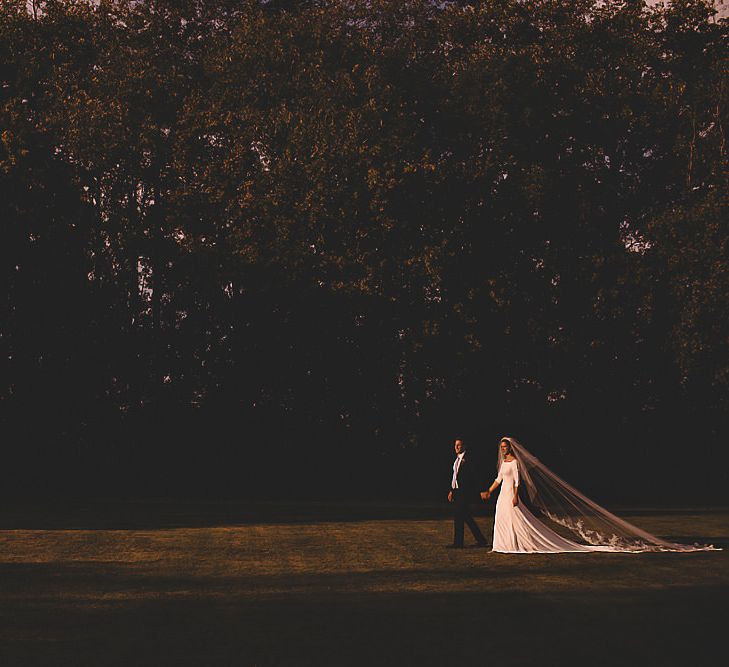 Bride wearing simple dress and extraordinary veil for sunset wedding shot