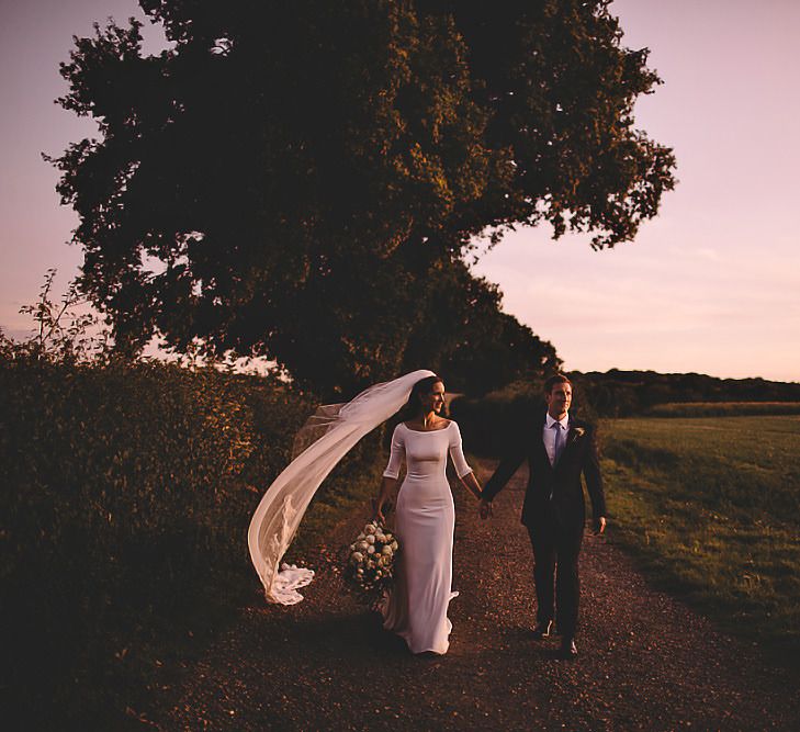 Bride wearing beautiful veil and white rose bouquet with groom wearing suit and pale blue tie