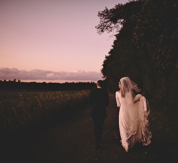 Bride and groom steal a moment for epic sunset wedding shot holding white rose bouquet