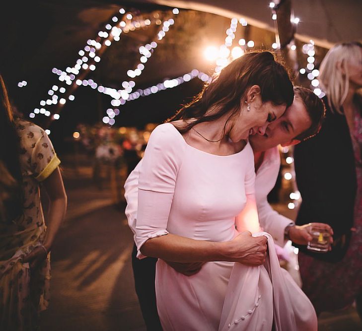 Bride and groom enjoy their tipi reception styled with fairy lights