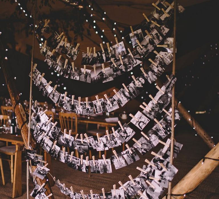 Black and white polaroid images hung with pegs at tipi garden party reception