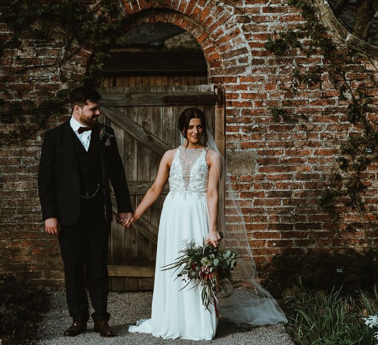 Bride in Maren Maggie Stottero Wedding Dress with Embellished Halterneck and Groom in Suit with Bow Tie