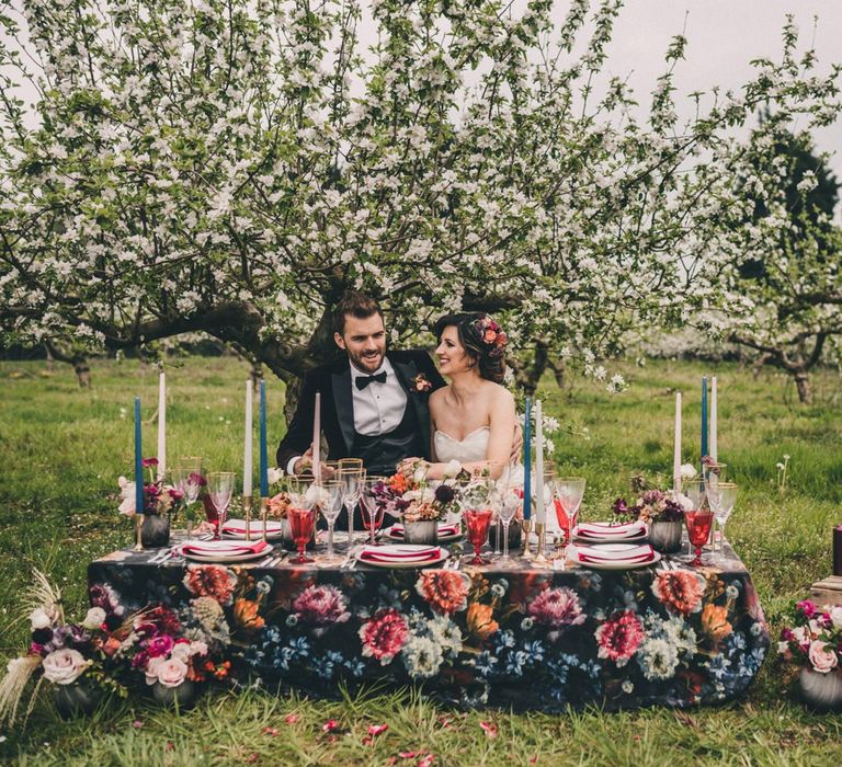 Elegant Bride and Groom Sitting at a Vibrant Floral Tablescape