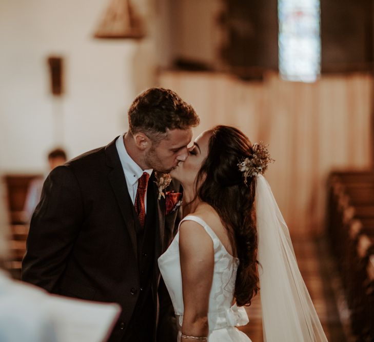 Bride and groom kissing at socially distanced church wedding ceremony