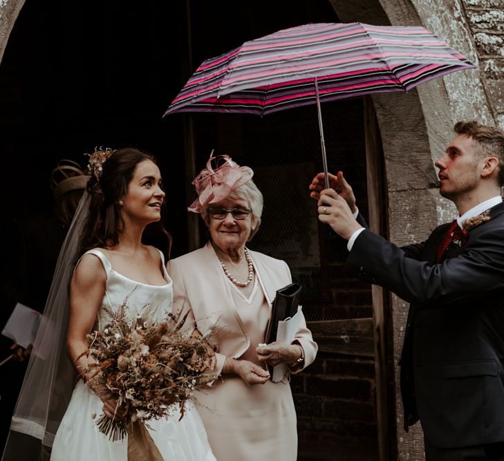 Groom sheltering his bride with an umbrella