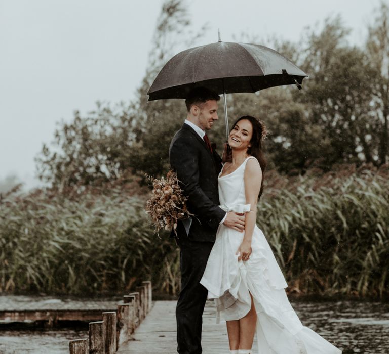 Bride and groom standing under an umbrella at September 2020 Wedding