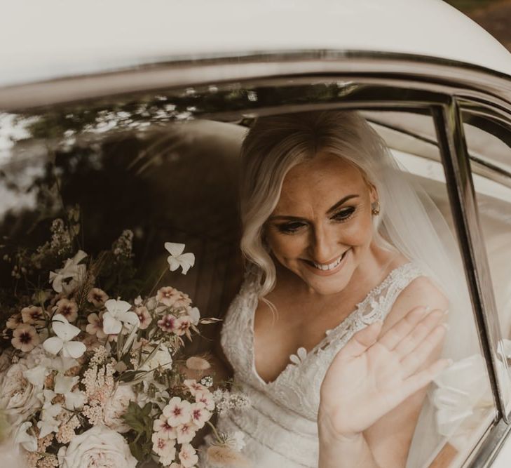 Bride in white wedding car on way to ceremony