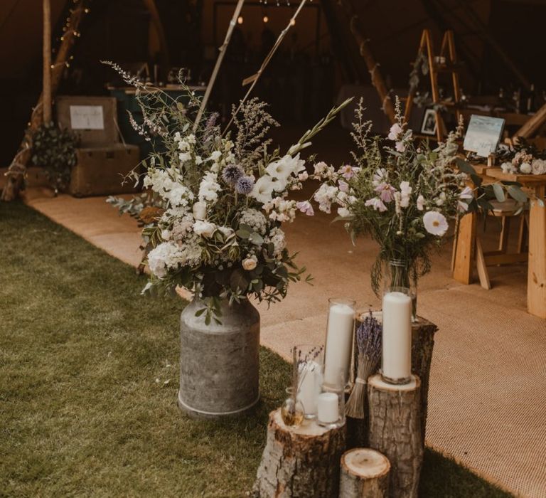 Teepee for wedding reception entrance with flowers in milk churns