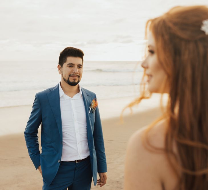 Groom In Navy Suit with Orange Buttonhole and Bride with Floral Hair Accessories