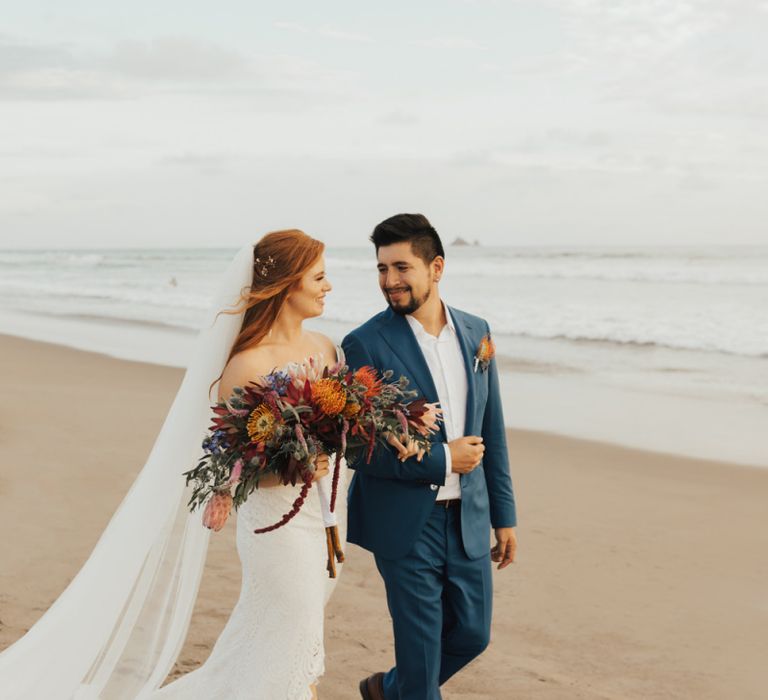 Bride and Groom On Beach After Ceremony With Orangey Flowers