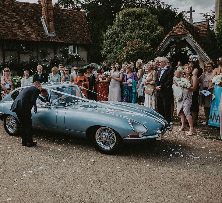 Bride and Groom Leaving the Church in a Blue E-Type Jaguar Wedding Car