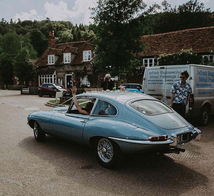 Bride and Groom Leaving the Church in a Blue E-Type Jaguar Wedding Car