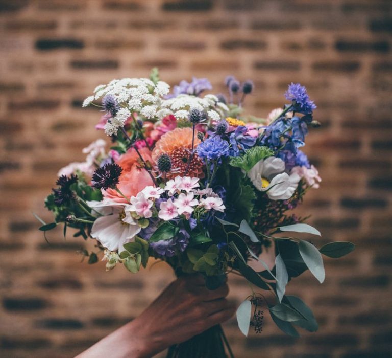 Beautiful wildflower wedding bouquets with pink and purple detail for city wedding with fairy light backdrop