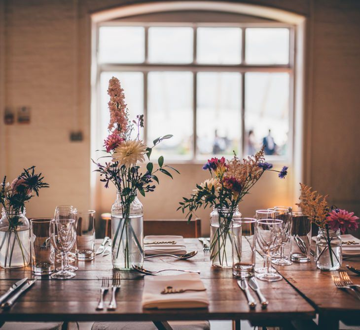 Table centrepiece with jam jar flower decor and fairy light backdrop with hoop details