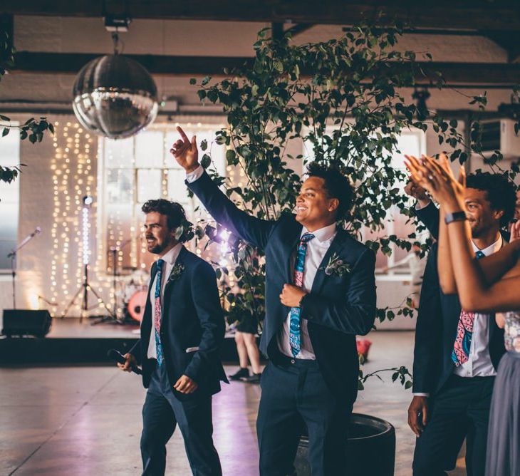 EWedding guests celebrate and industrial styled venue with fairy light backdrop in London