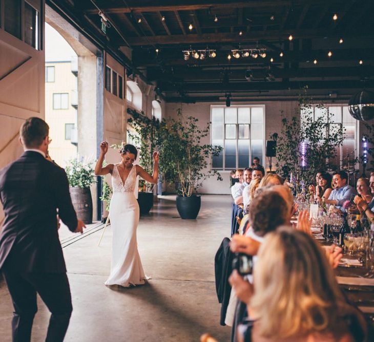 Bride and groom celebrate and industrial styled venue with fairy light backdrop in London